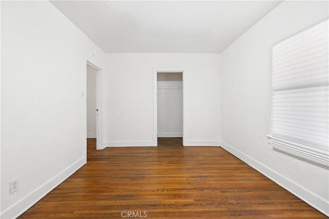 unfurnished bedroom featuring a closet, baseboards, and dark wood-style floors