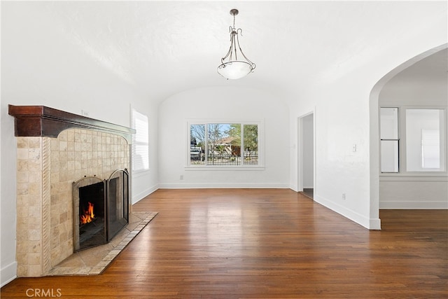 unfurnished living room with a tile fireplace, baseboards, and wood-type flooring