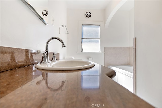 bathroom with visible vents, a washtub, and a sink