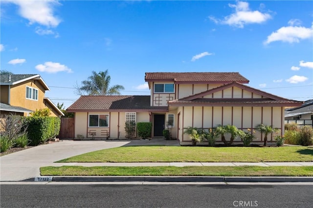 view of front facade with fence, a tile roof, and a front yard