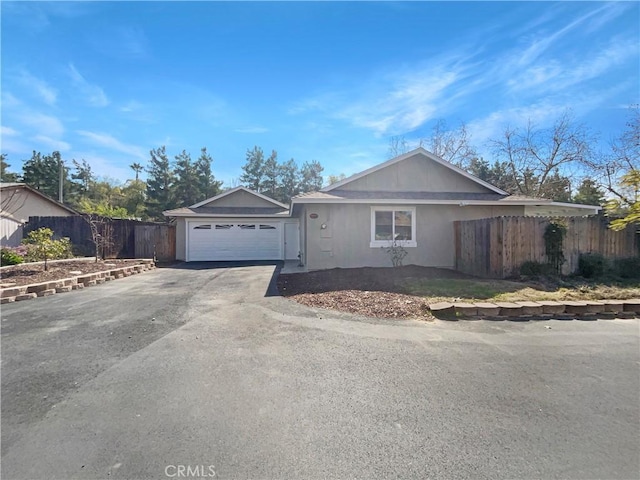 ranch-style house featuring a garage, fence, and driveway