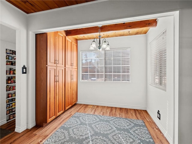 dining room featuring a notable chandelier, light wood-style flooring, wooden ceiling, and baseboards