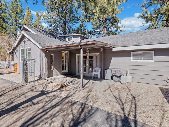 back of house featuring a patio area, french doors, board and batten siding, and roof with shingles