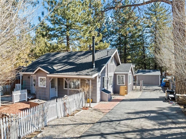 view of front of home featuring a fenced front yard and a shingled roof