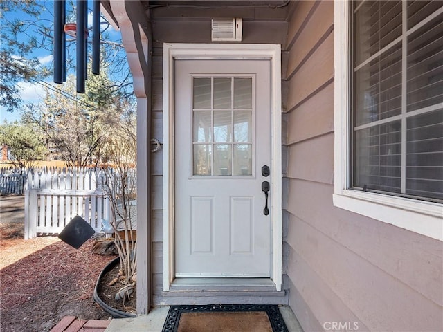 doorway to property featuring fence and visible vents