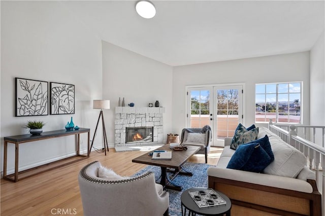 living area featuring a fireplace, baseboards, wood finished floors, and french doors