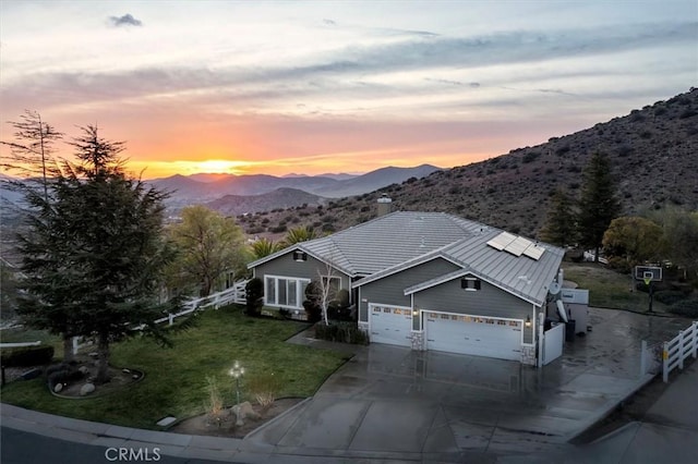 view of front of property featuring a garage, a mountain view, a front lawn, and fence