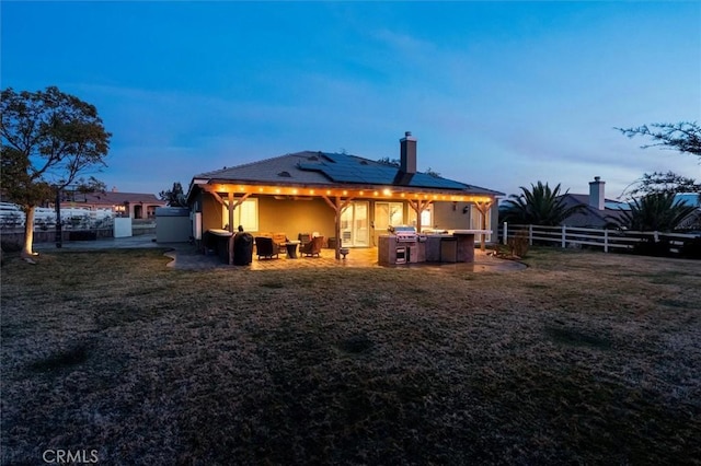 back of house at dusk with a fenced backyard