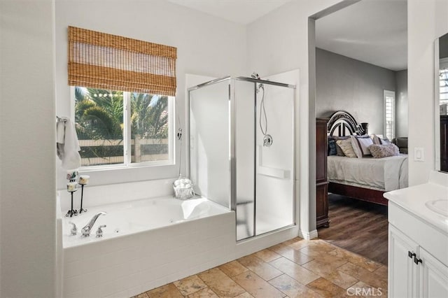 ensuite bathroom with a stall shower, ensuite bath, wood finished floors, a garden tub, and vanity