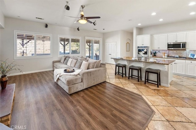 living area with light wood finished floors, recessed lighting, visible vents, a ceiling fan, and baseboards