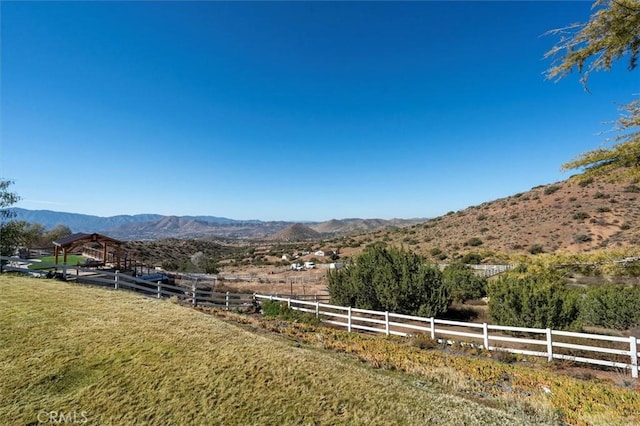 view of yard with fence, a mountain view, and a rural view