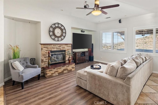 living room with baseboards, visible vents, a glass covered fireplace, ceiling fan, and wood finished floors