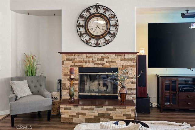 sitting room with a brick fireplace, dark wood finished floors, and baseboards