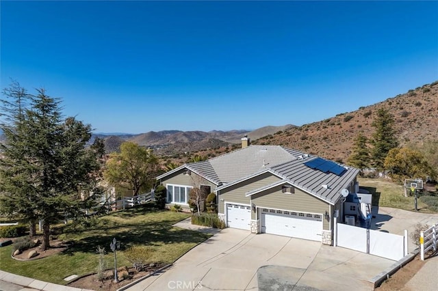 view of front facade featuring an attached garage, fence, a mountain view, and roof mounted solar panels