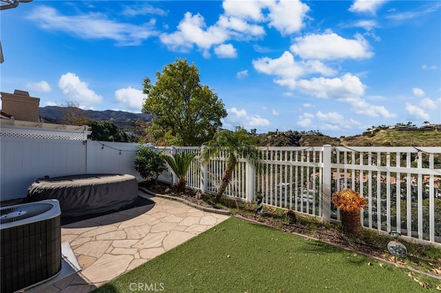 view of patio with a fenced backyard, central AC unit, and a mountain view