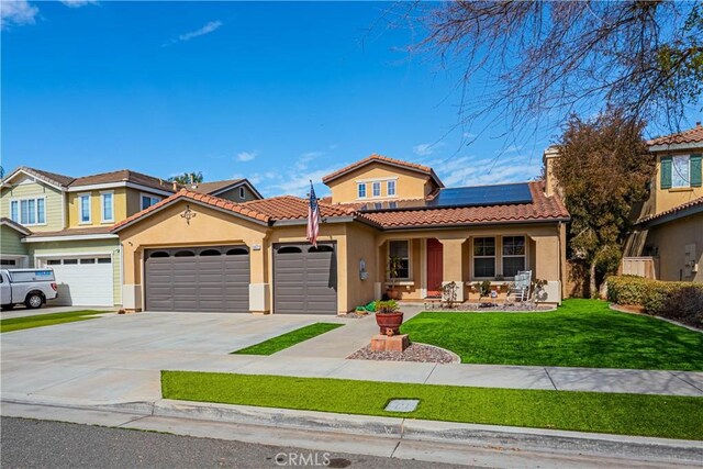 view of front facade with stucco siding, a porch, a front yard, roof mounted solar panels, and a garage