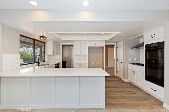 kitchen featuring a peninsula, dobule oven black, and light countertops