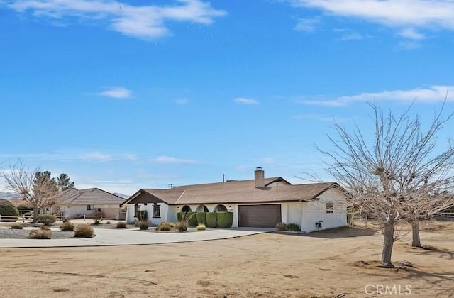 single story home featuring a garage, driveway, and a chimney