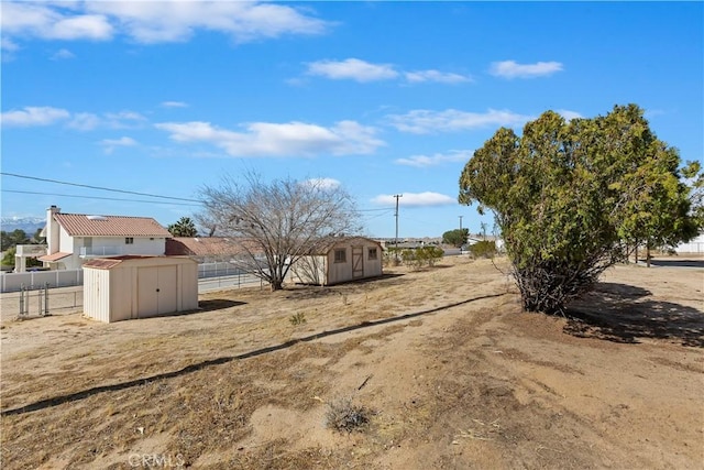 view of yard with fence, a storage unit, and an outbuilding