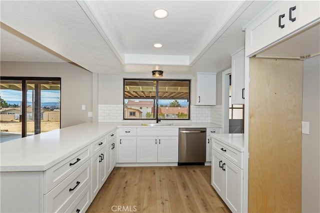 kitchen with light countertops, dishwasher, a peninsula, and white cabinetry