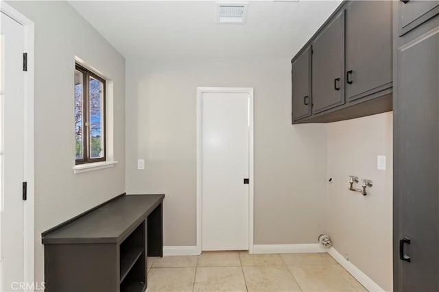 laundry area featuring light tile patterned flooring, hookup for a washing machine, visible vents, baseboards, and cabinet space