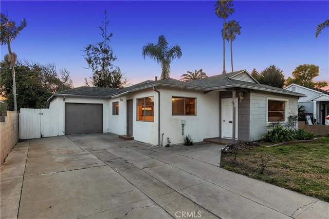 ranch-style house with an attached garage, concrete driveway, and stucco siding