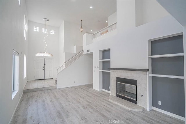 unfurnished living room with baseboards, light wood-style flooring, and built in features