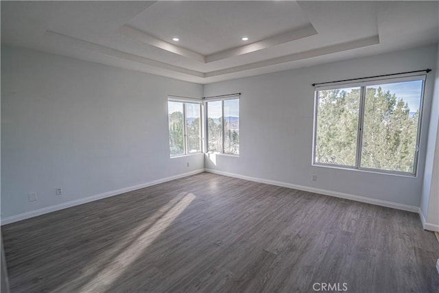 unfurnished room with dark wood-style floors, baseboards, a tray ceiling, and recessed lighting