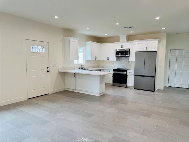 kitchen with stainless steel appliances, light countertops, visible vents, white cabinetry, and a peninsula