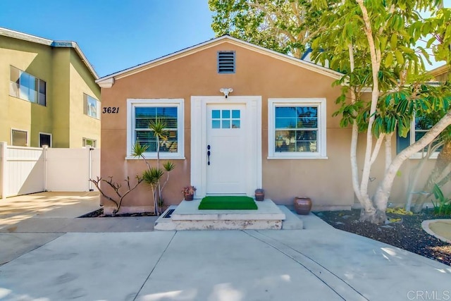 entrance to property featuring fence and stucco siding