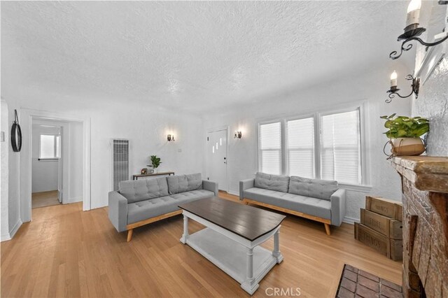 living room featuring light wood-style floors, a wealth of natural light, and a textured ceiling