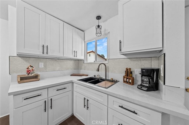 kitchen featuring white cabinets, a sink, and hanging light fixtures