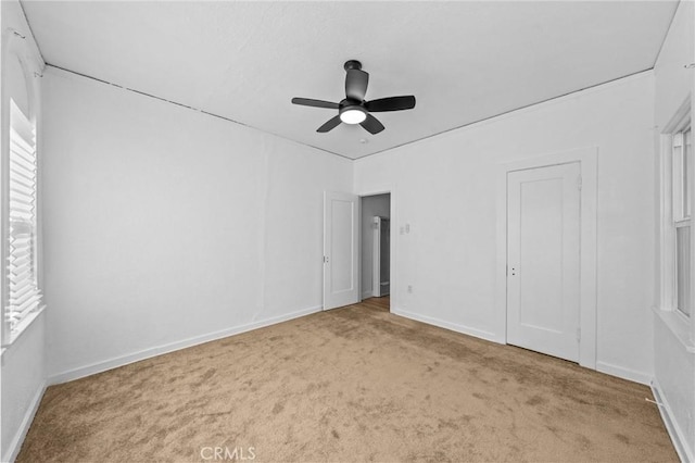 unfurnished bedroom featuring light carpet, a ceiling fan, and baseboards