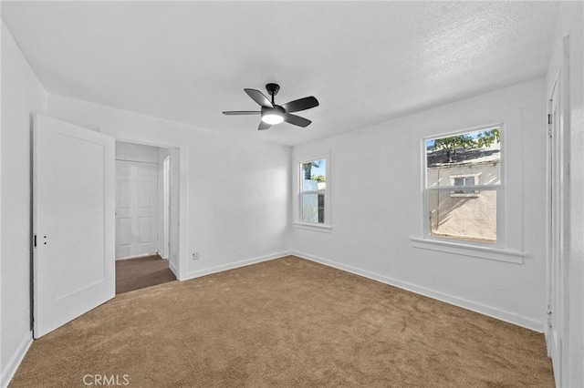 empty room featuring carpet, plenty of natural light, baseboards, and ceiling fan