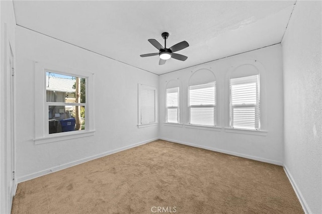 spare room featuring baseboards, a ceiling fan, and light colored carpet