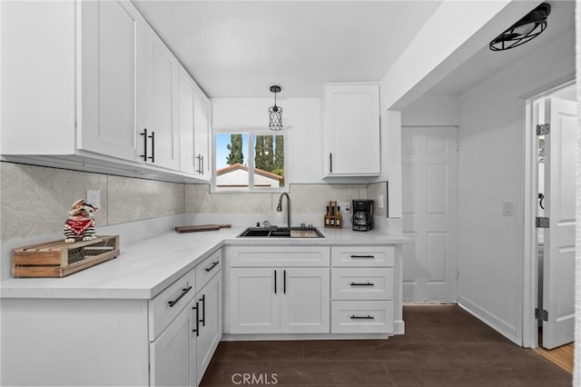 kitchen featuring white cabinets, light countertops, a sink, and decorative light fixtures