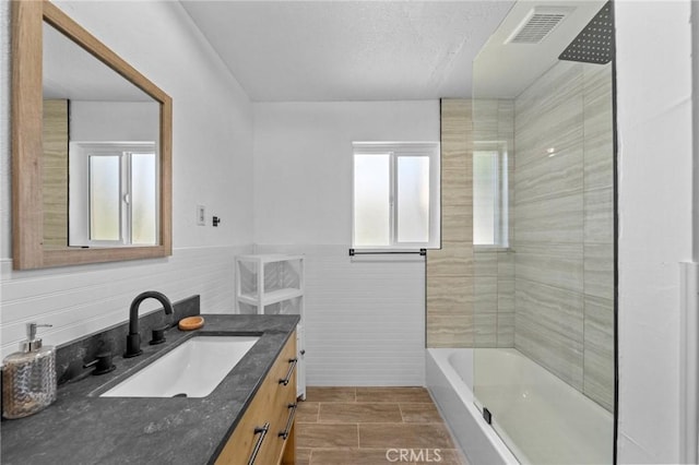 bathroom with wainscoting, visible vents, vanity, and shower / tub combination