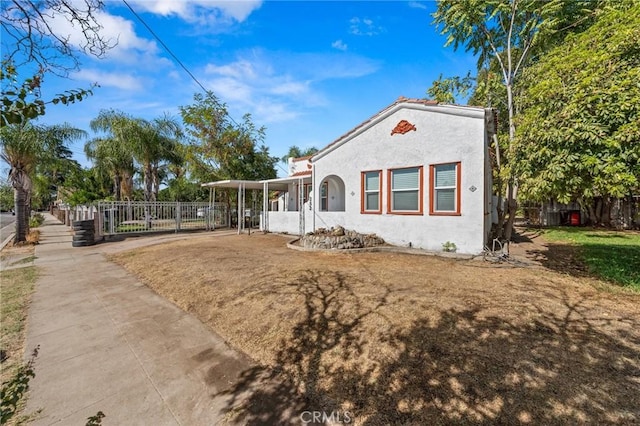 mediterranean / spanish home with a front yard, fence, and stucco siding