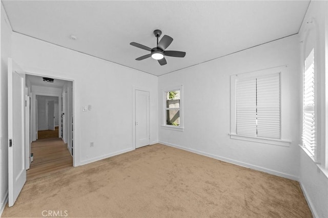 unfurnished room featuring a ceiling fan, light carpet, and baseboards