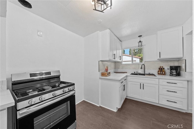 kitchen featuring light countertops, stainless steel gas range oven, a sink, and white cabinetry