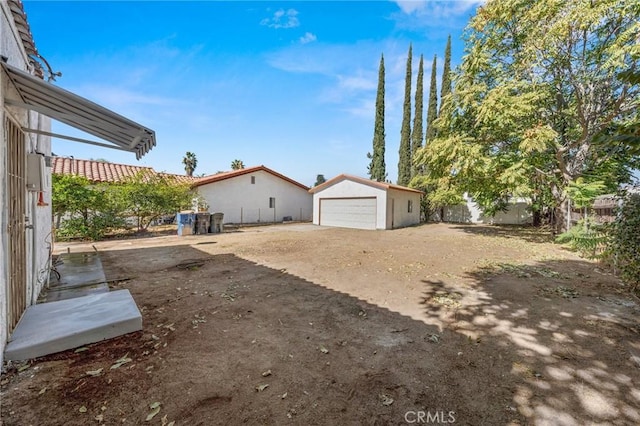 view of yard featuring an outdoor structure, a detached garage, and fence