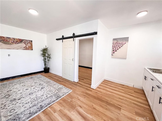 interior space featuring light wood-style floors, a barn door, and baseboards