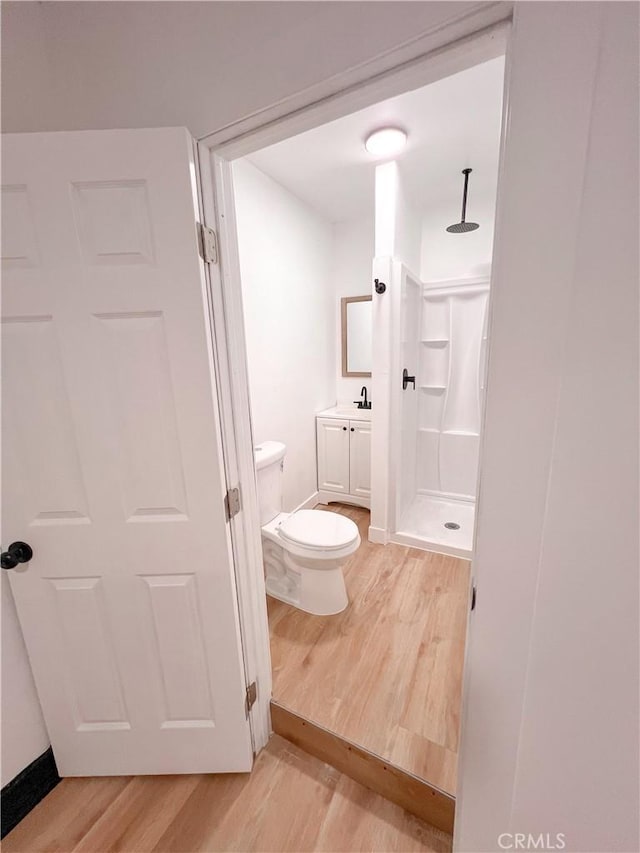 full bath featuring vanity, a stall shower, wood finished floors, and toilet