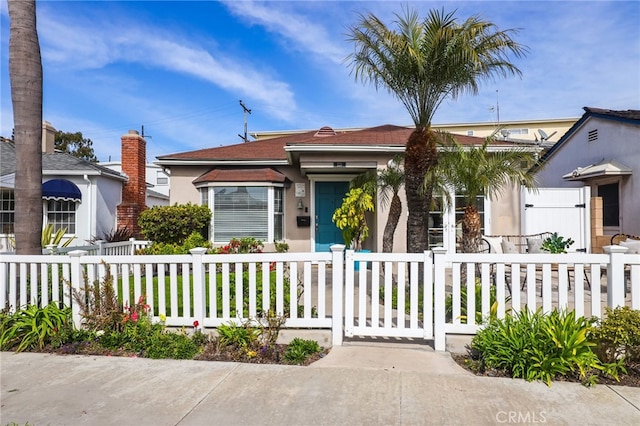 view of front facade with a fenced front yard, a gate, and stucco siding