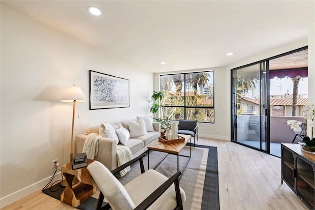 living area with light wood-style floors, baseboards, and recessed lighting