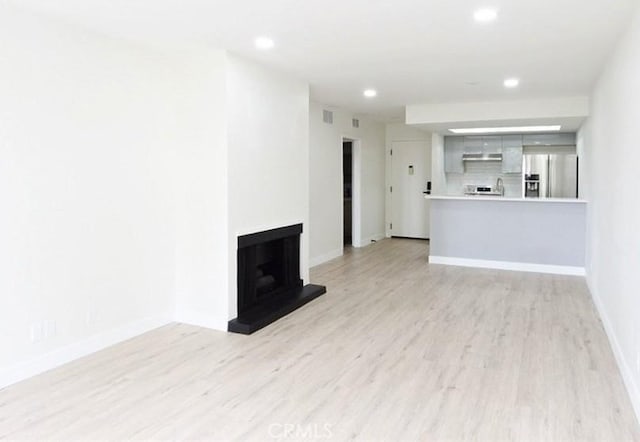 1745 Camino Palmero St Unit 537, Los Angeles, CA 90046 - unfurnished living room with light wood-style floors, a fireplace with raised hearth, baseboards, and recessed lighting