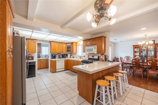 kitchen with appliances with stainless steel finishes, a breakfast bar, light countertops, and a peninsula