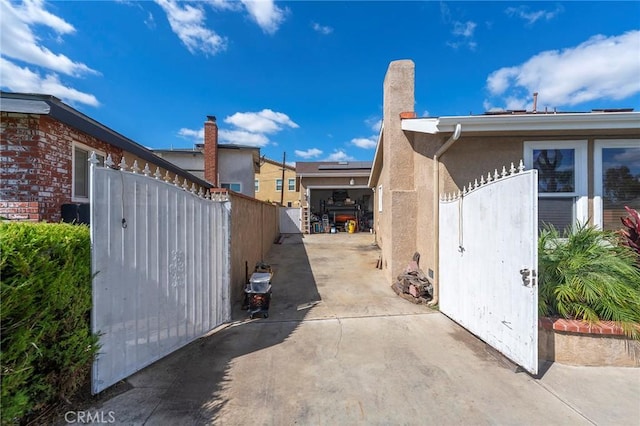 view of side of home with fence, a gate, and stucco siding