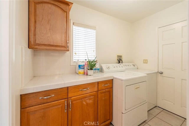 washroom with cabinet space, light tile patterned floors, and washer and dryer