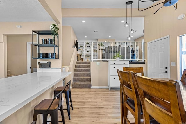 kitchen featuring light wood finished floors, light stone counters, decorative light fixtures, white cabinetry, and recessed lighting